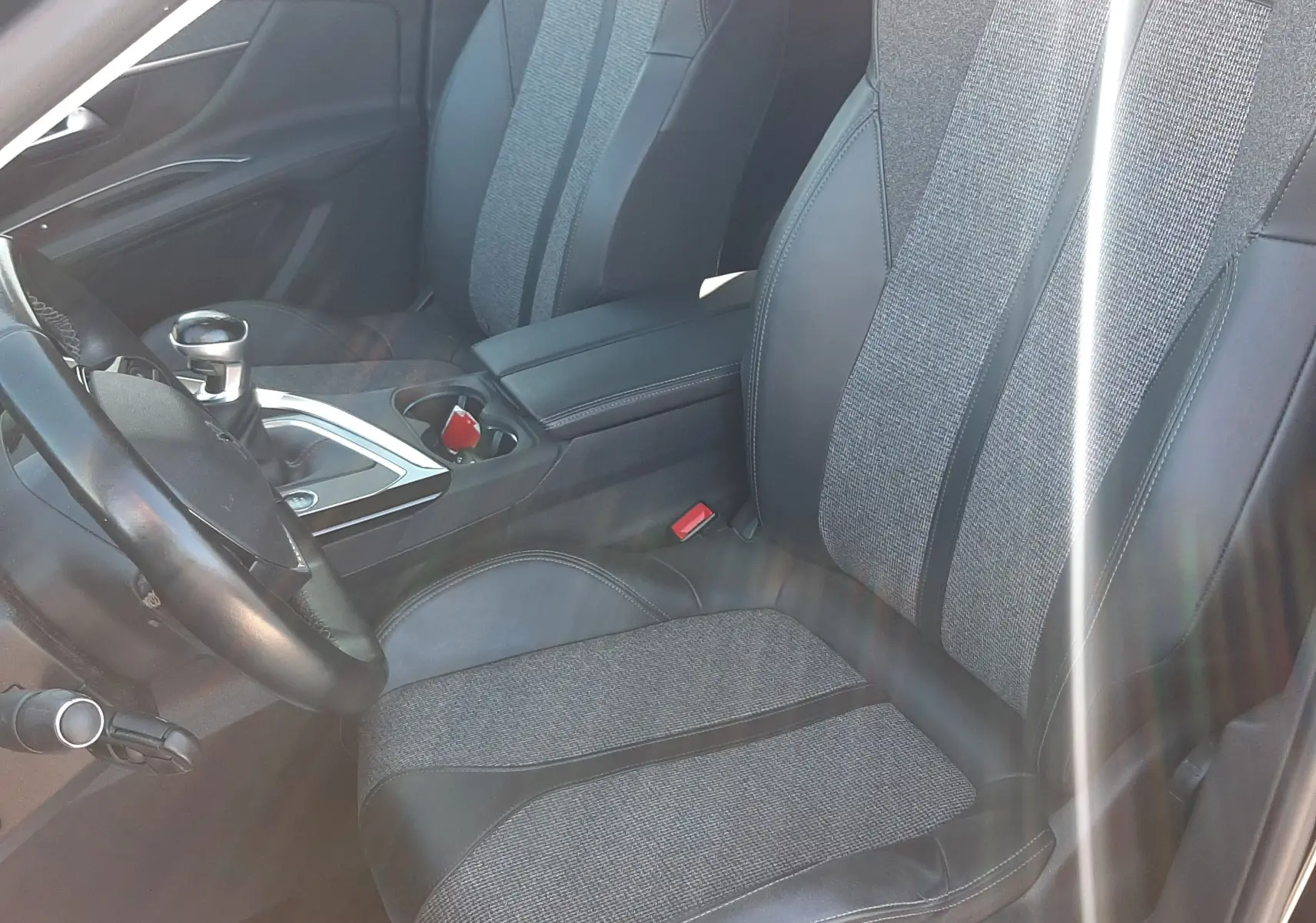 Vue intérieure côté conducteur du Peugeot 3008 noir, sièges bi-matière tissu et cuir avec console centrale et levier de vitesse manuelle.