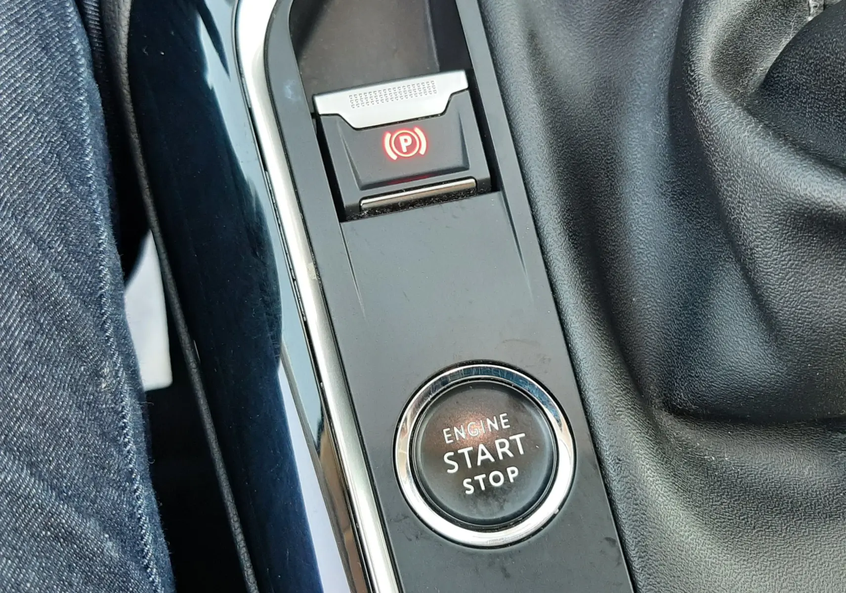 Gros plan sur la console centrale noire du Peugeot 3008 2019, montrant le bouton Start/Stop et le frein à main électronique.