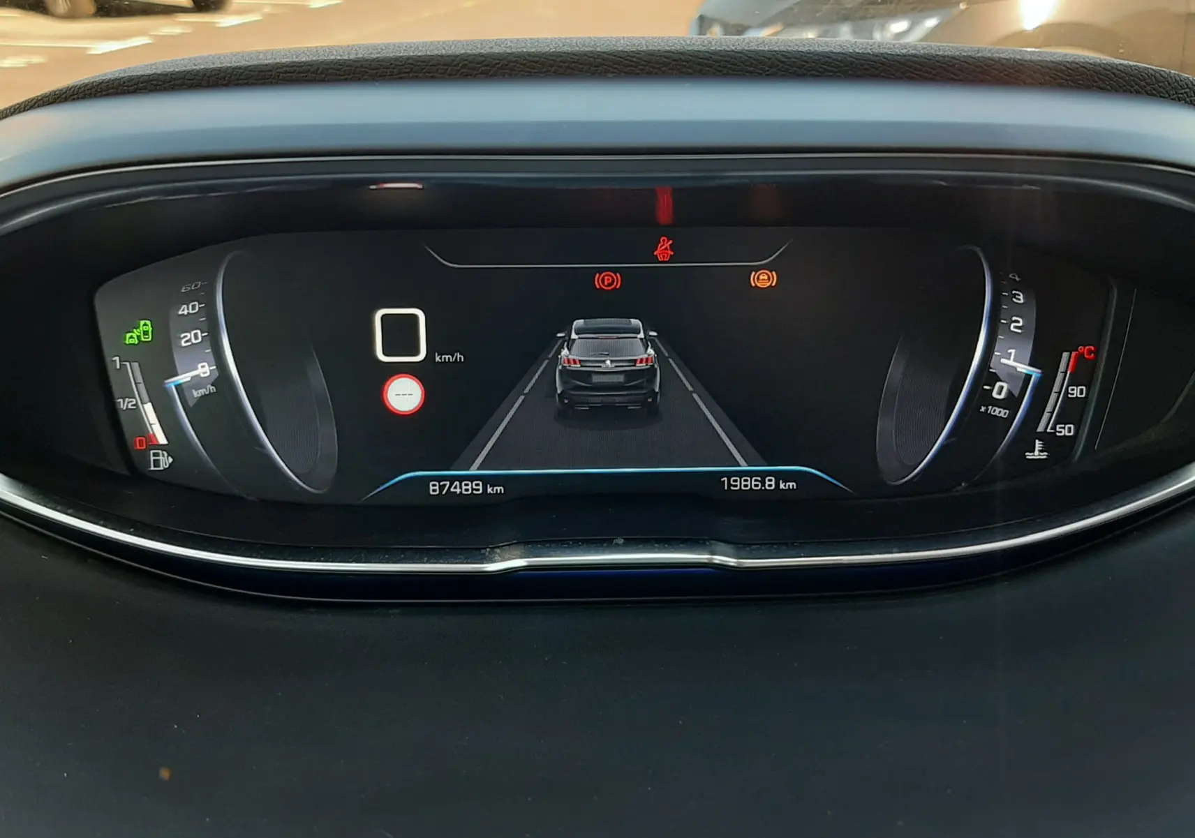 Vue rapprochée du tableau de bord numérique du Peugeot 3008 noir, affichant la vitesse à 0 km/h et un véhicule devant.
