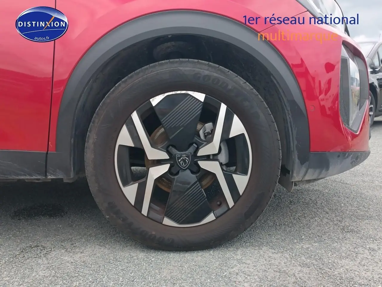 Gros plan sur la roue avant gauche rouge elixir d’un Peugeot 2008 1.2 100 allure avec jante alu distinctive.