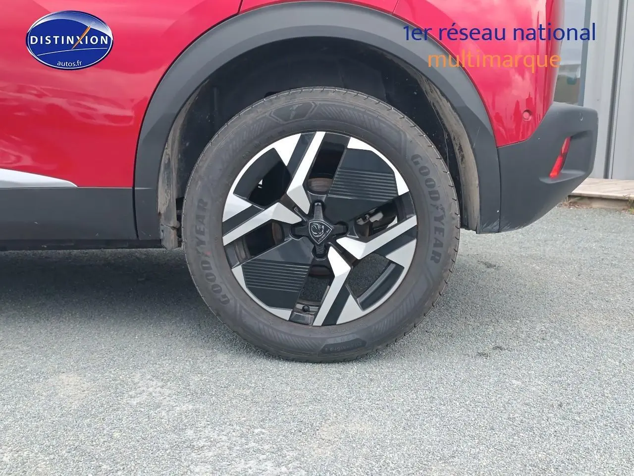 Gros plan sur la roue arrière droite du Peugeot 2008 rouge elixir avec jante alu au design géométrique.