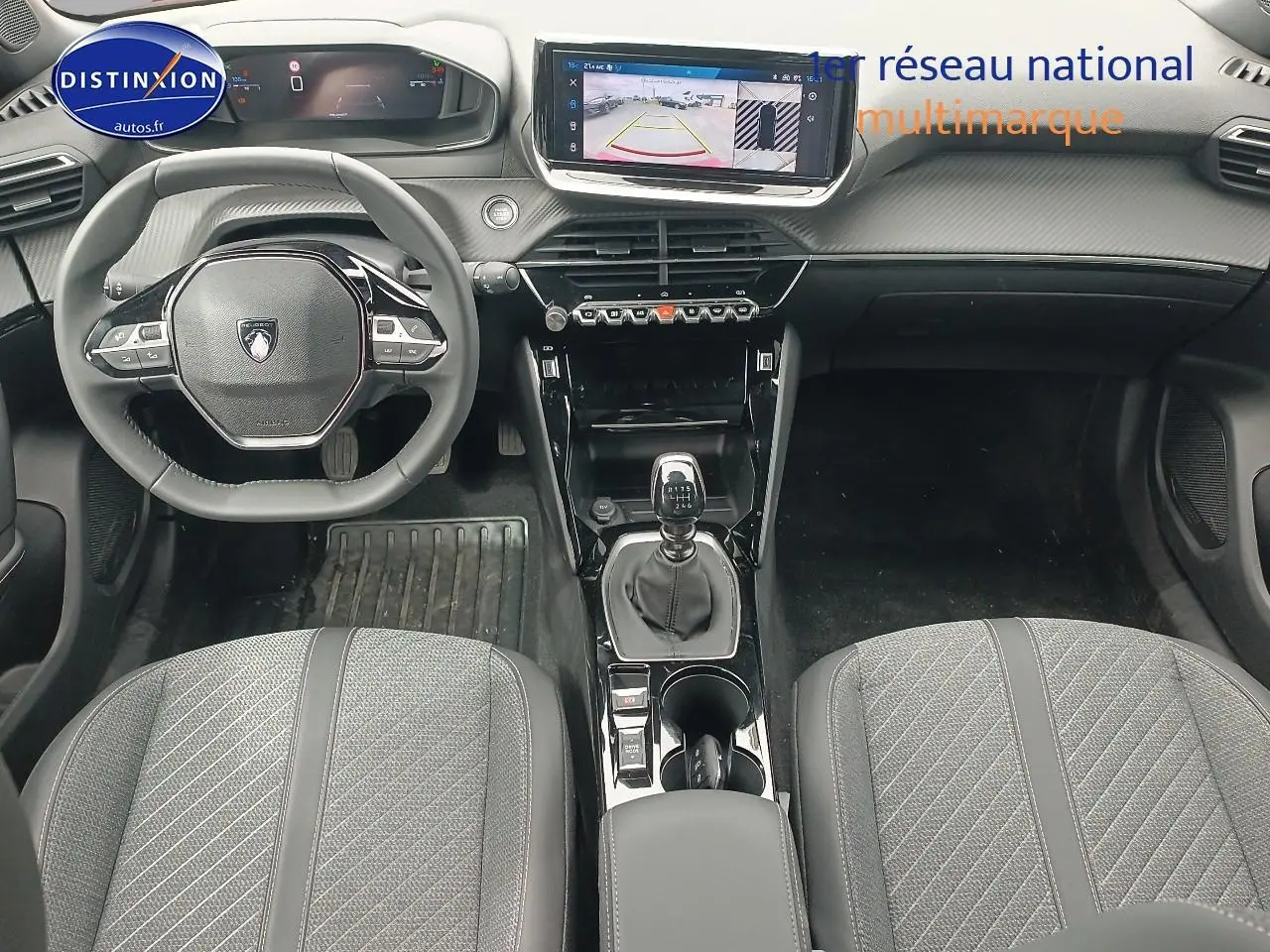 Vue intérieure avant du Peugeot 2008 1.2 100 allure avec tableau de bord numérique et boîte manuelle, sièges tissu gris.