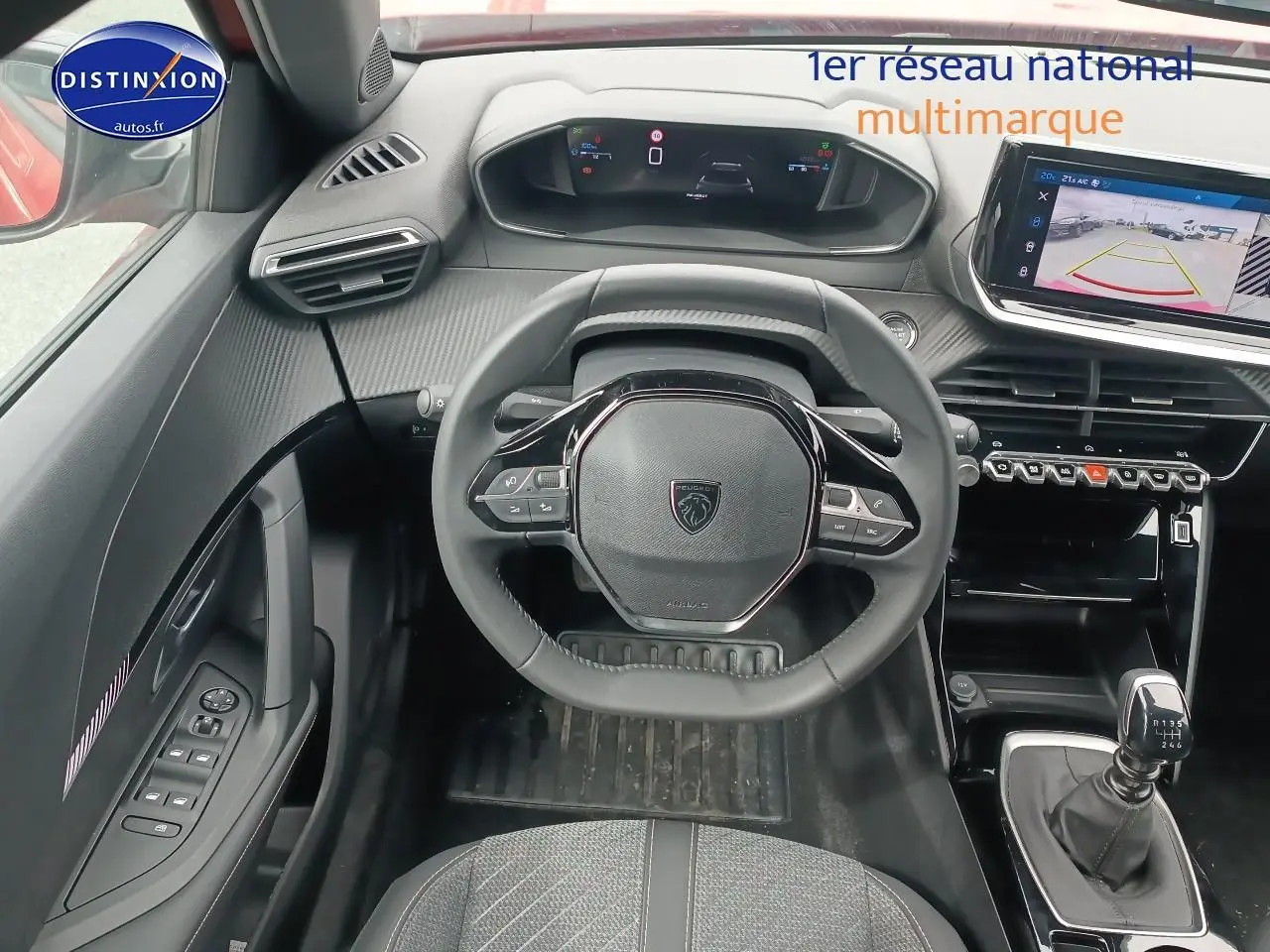 Vue intérieure avant centrée sur le volant compact et le tableau de bord numérique du Peugeot 2008 rouge Elixir.