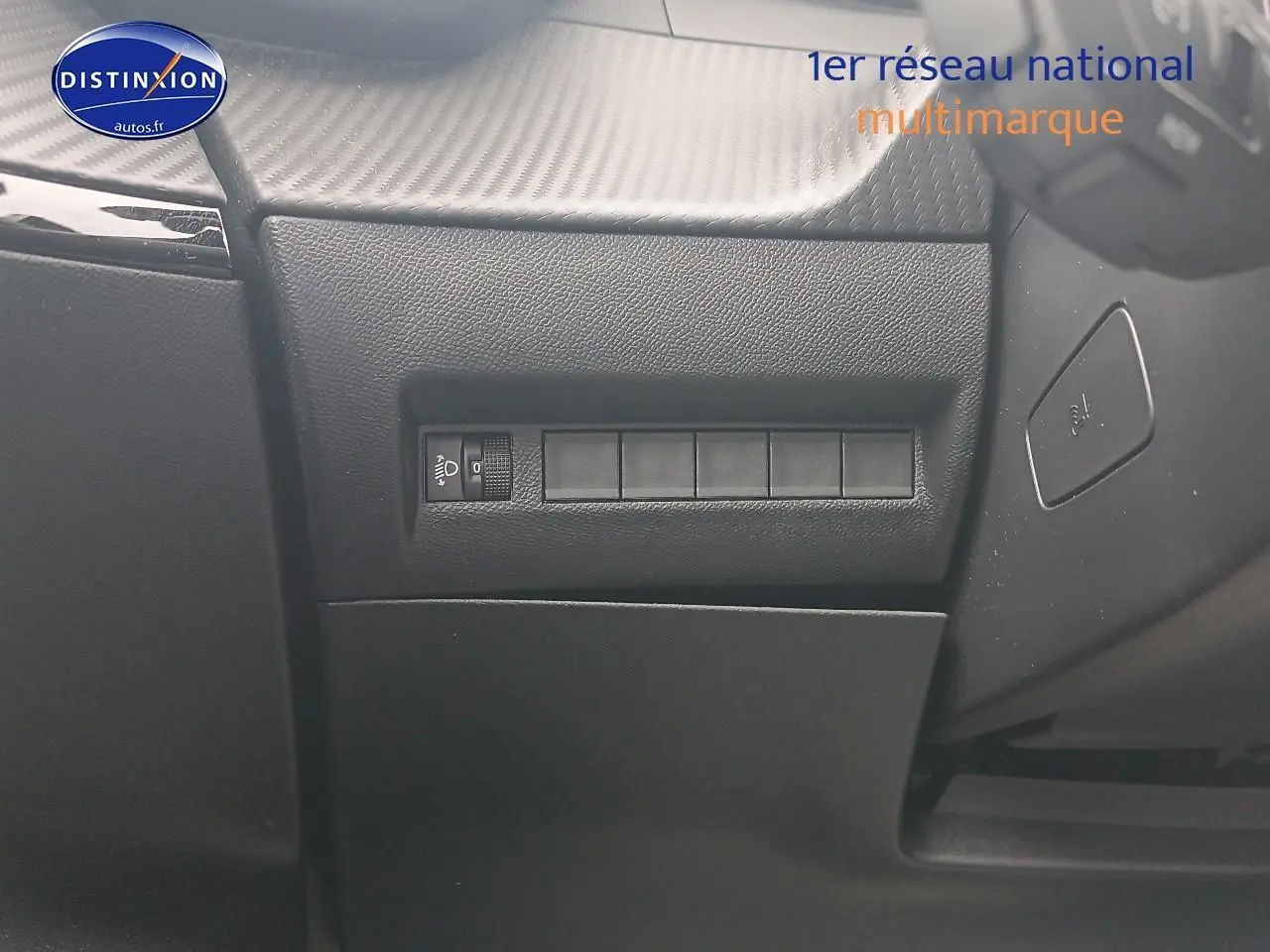 Détail intérieur du tableau de bord côté gauche avec commande de réglage des phares sur Peugeot 2008 Rouge Elixir.