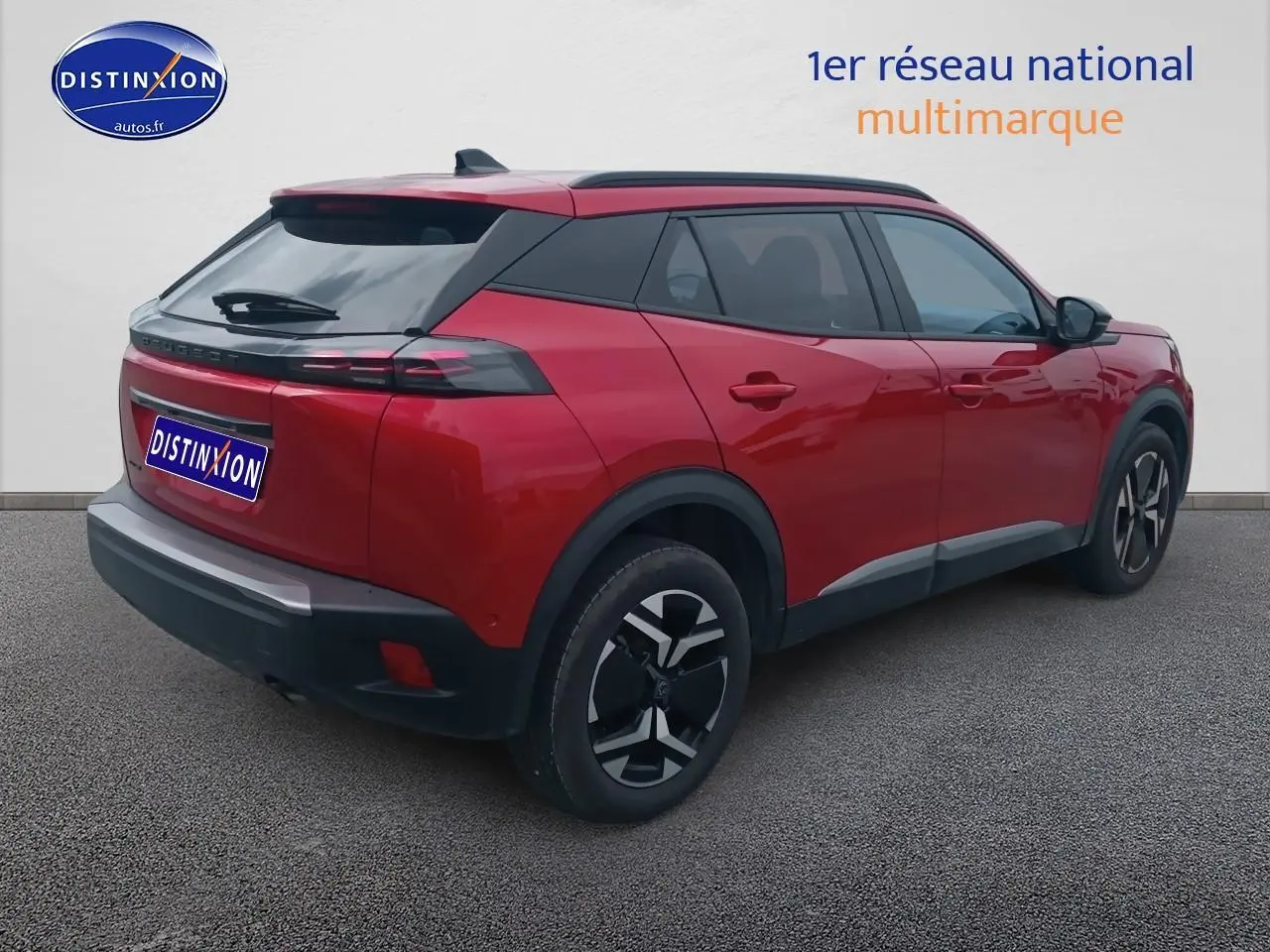 Vue 3/4 arrière droit d'un Peugeot 2008 rouge élixir avec jantes alu et vitres arrière teintées.