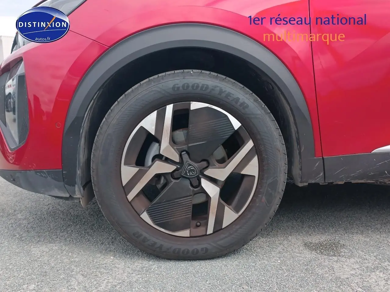 Gros plan sur la roue avant gauche avec jante alu du Peugeot 2008 rouge elixir, montrant le passage de roue noir.