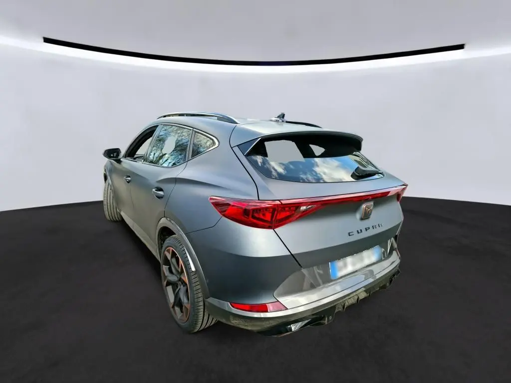 Vue 3/4 arrière droite d’un CUPRA Formentor gris foncé mat, avec feux arrière allongés et jantes noires aux accents cuivrés.