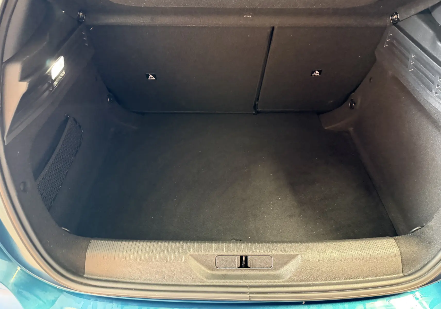 Coffre ouvert vu de dessus d'une Peugeot 308 Hybrid 145 bleu obsession, espace de rangement propre et spacieux.