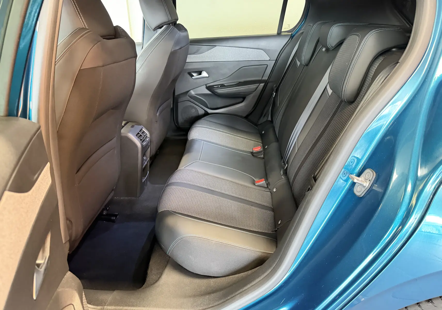 Vue intérieure côté arrière droit de la Peugeot 308 Hybrid 145 Allure bleu obsession, montrant les sièges arrière en tri-matières.
