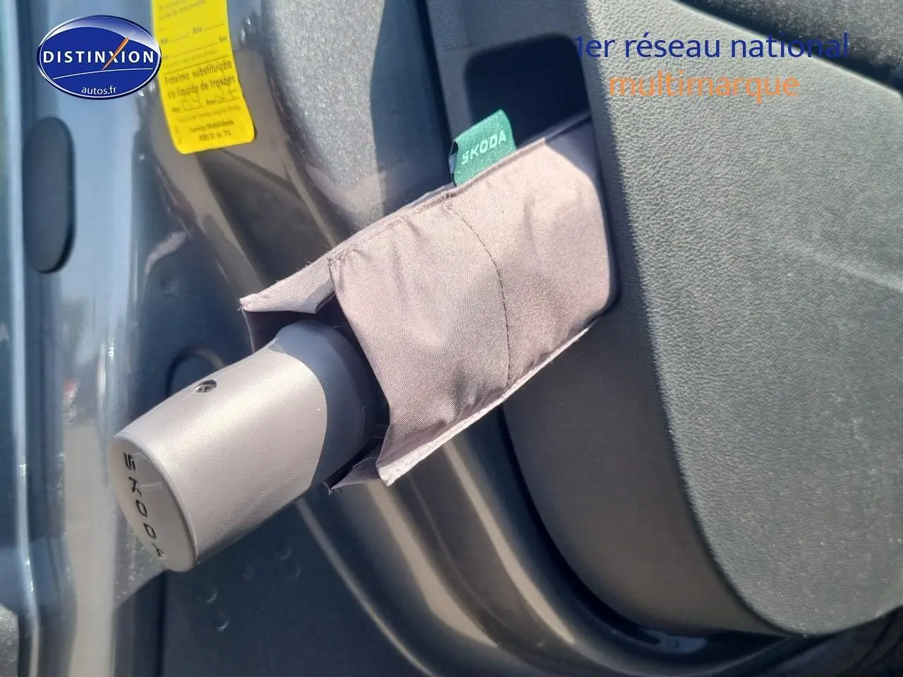 Détail du rangement porte-parapluie gris avec étiquette Skoda sur la porte intérieure d'un Skoda Kamiq gris graphite.