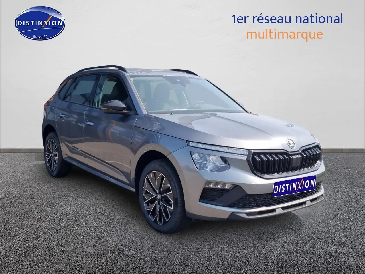 Vue 3/4 avant d'un Skoda Kamiq gris graphite avec barres de toit noires et jantes alliage distinctives.