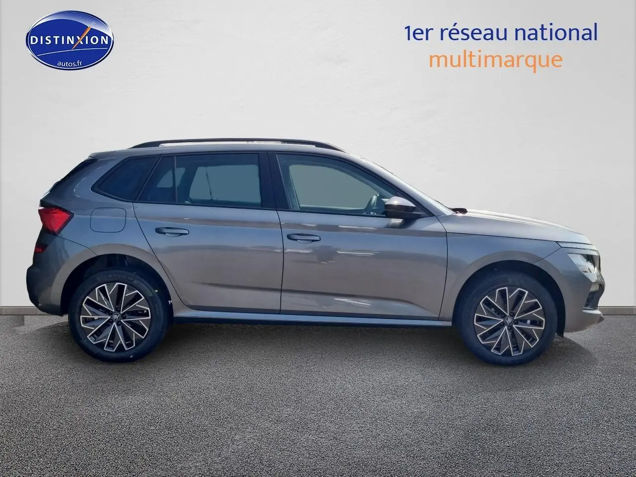 Profil côté gauche d'un Skoda Kamiq gris graphite 2025 avec barres de toit noires et jantes stylisées.