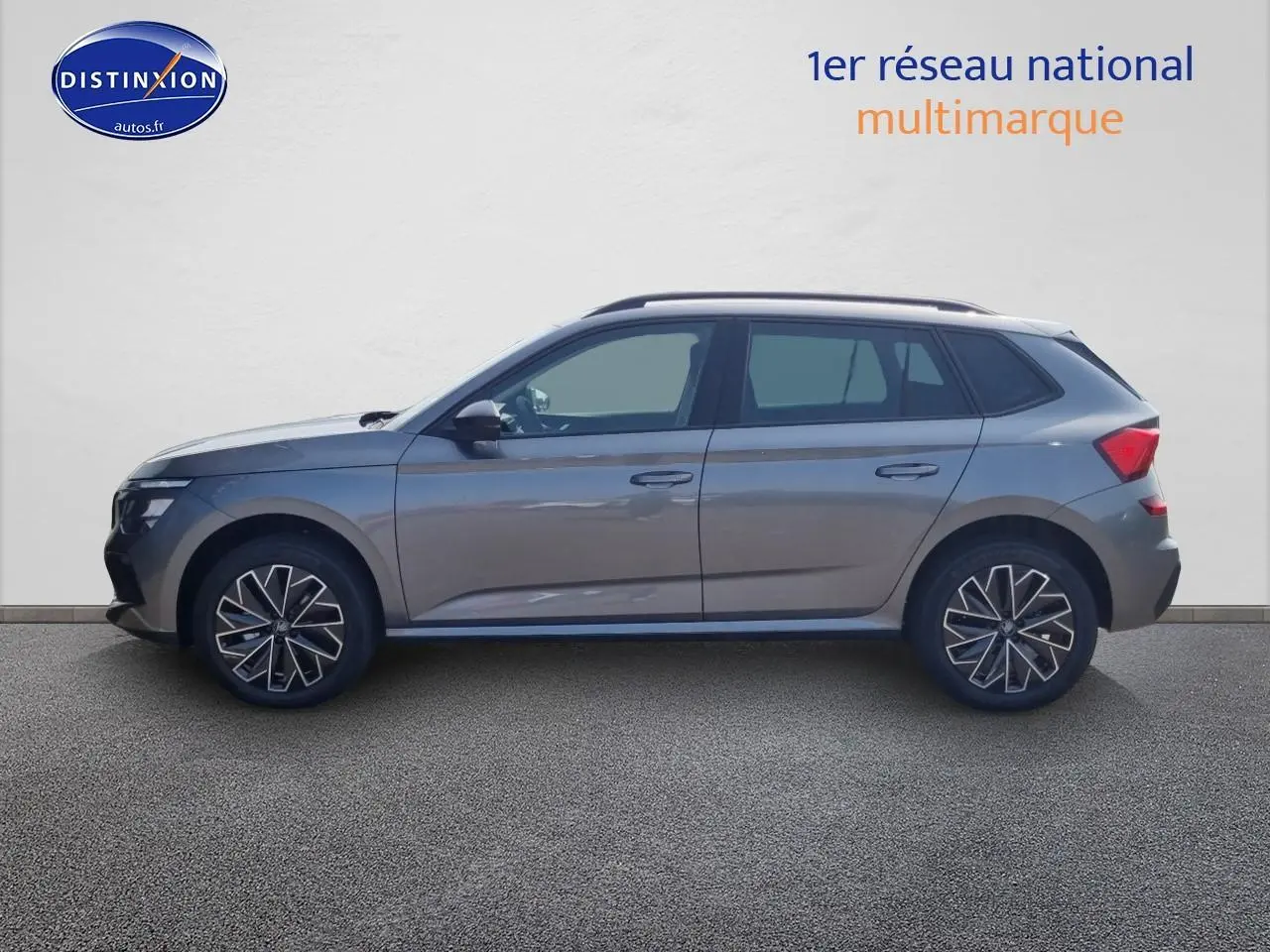 Vue de profil côté gauche d'un Skoda Kamiq gris graphite avec barres de toit noires et jantes stylisées.