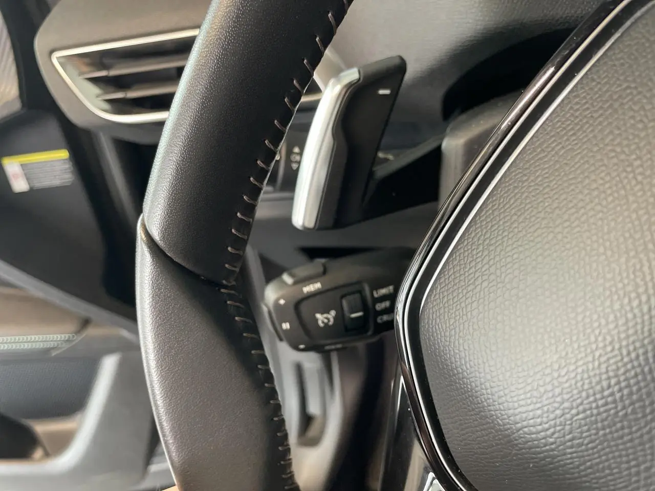 Gros plan sur le volant en cuir noir Mistral du Peugeot 5008 2024, avec commandes intégrées et palettes au volant.