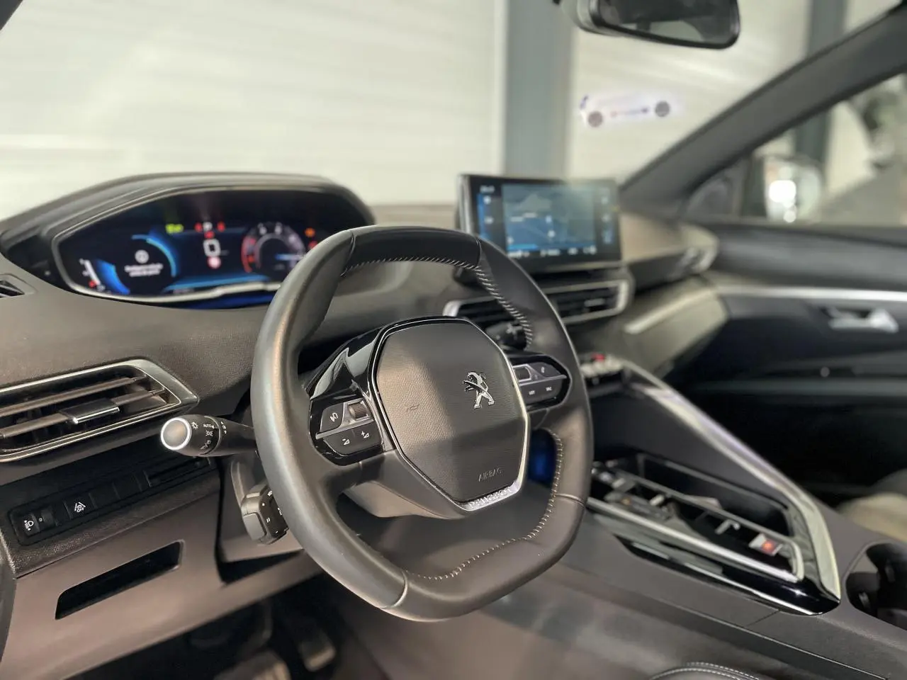 Intérieur du Peugeot 5008 2024 vu côté conducteur, volant compact cuir noir et tableau de bord numérique.