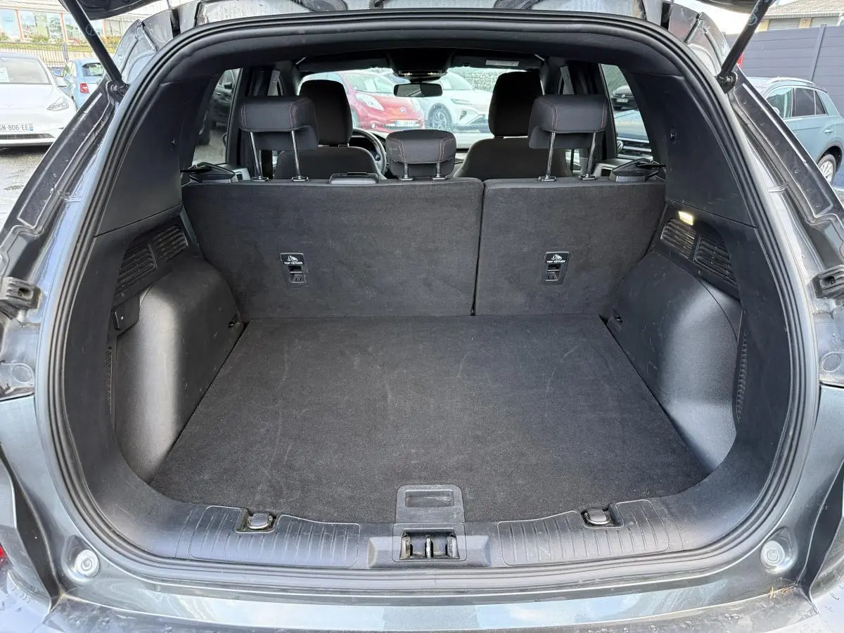 Coffre ouvert d'un Ford Kuga gris 2022, vue arrière montrant l'espace de chargement et la banquette arrière noire.