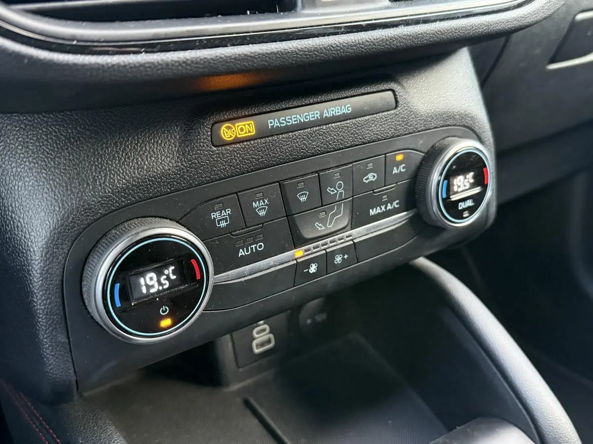 Gros plan sur la console centrale noire du Ford Kuga 2022 avec commandes de climatisation automatique bi-zone.