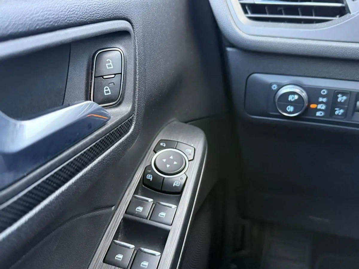 Détail des commandes de porte côté conducteur du Ford Kuga gris 2022, avec boutons de verrouillage et réglage des rétroviseurs.