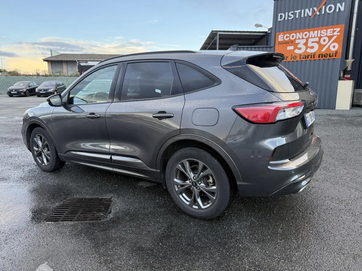 Ford Kuga gris métallisé vu de profil côté gauche, avec vitres arrière surteintées et jantes alliage 18 pouces.