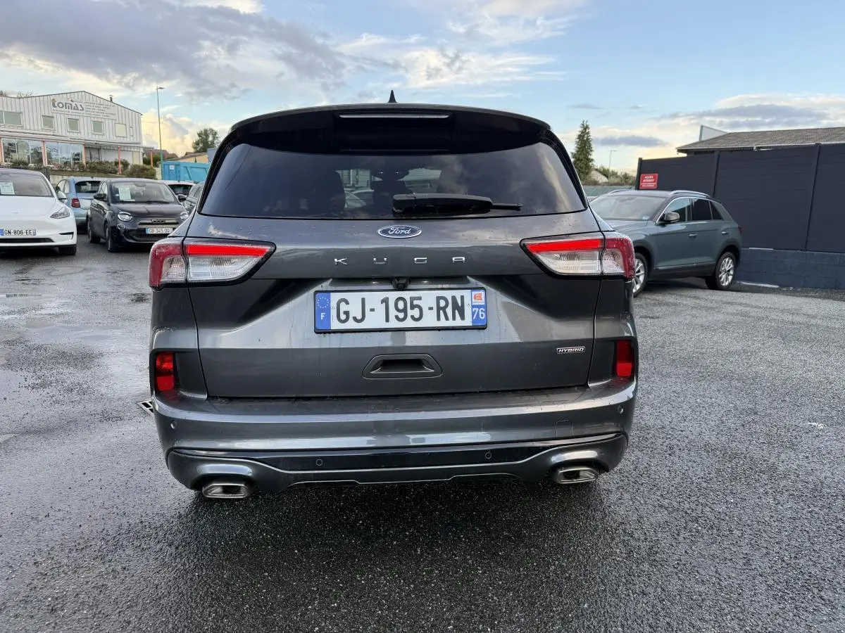 Vue arrière d'un Ford Kuga gris métallisé 2022 avec double sortie d'échappement et badges Hybrid et ST-Line.