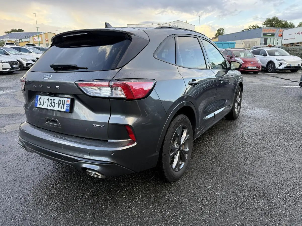 Vue 3/4 arrière droite d'un Ford Kuga gris métallisé avec vitres surteintées et double sortie d'échappement ST-Line.