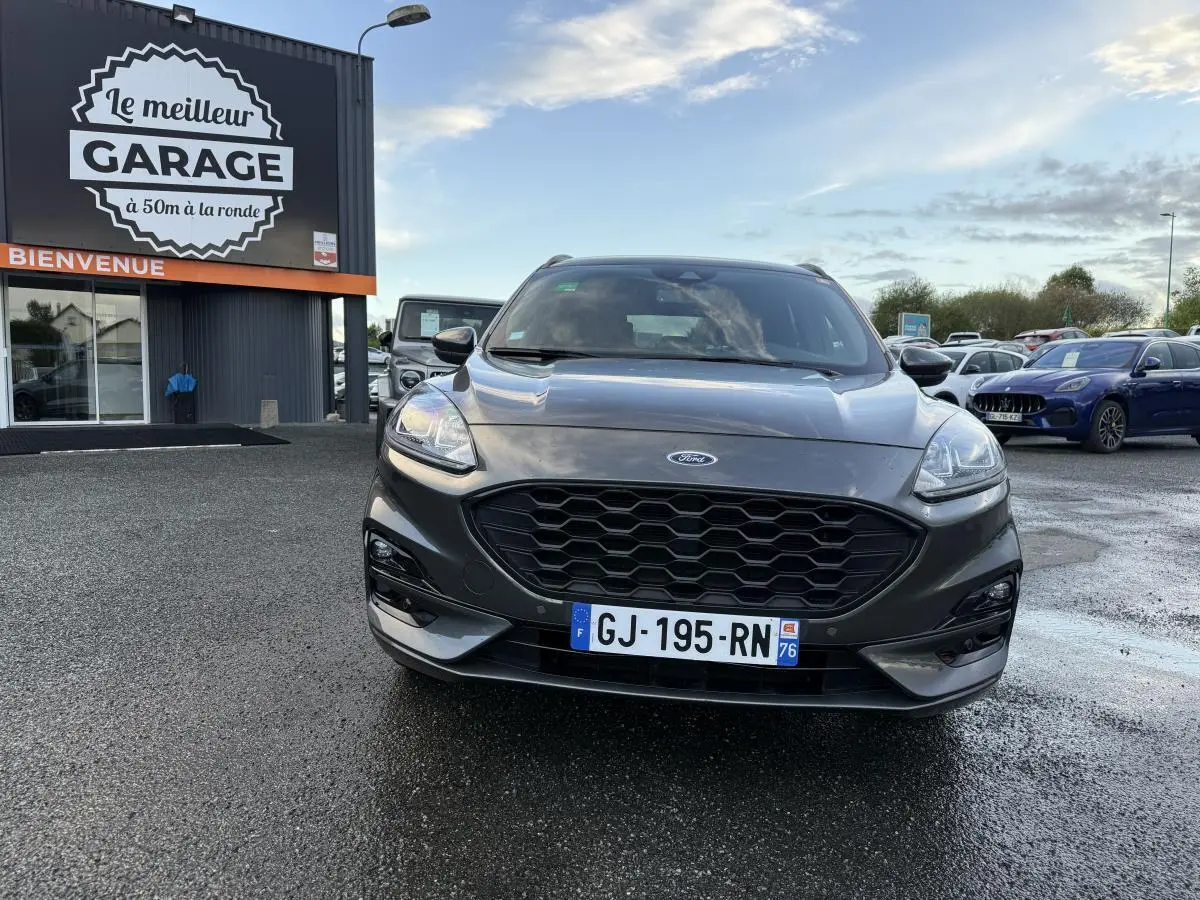 Vue frontale d'un Ford Kuga gris métallisé avec calandre noire et double sortie d'échappement ST-Line visible.