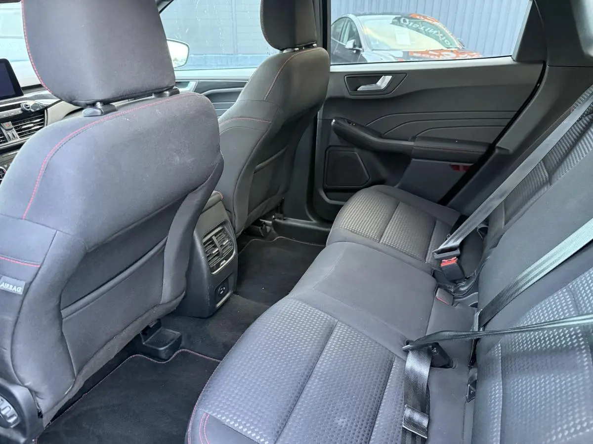 Vue intérieure arrière côté droit du Ford Kuga 2022 gris, sièges tissu noir avec surpiqûres rouges et ceintures de sécurité.