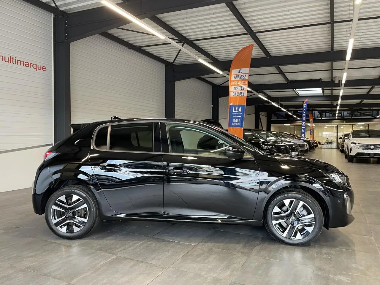 Peugeot 208 noire vue de profil côté gauche, avec jantes alliage bi-ton et vitres teintées en showroom.