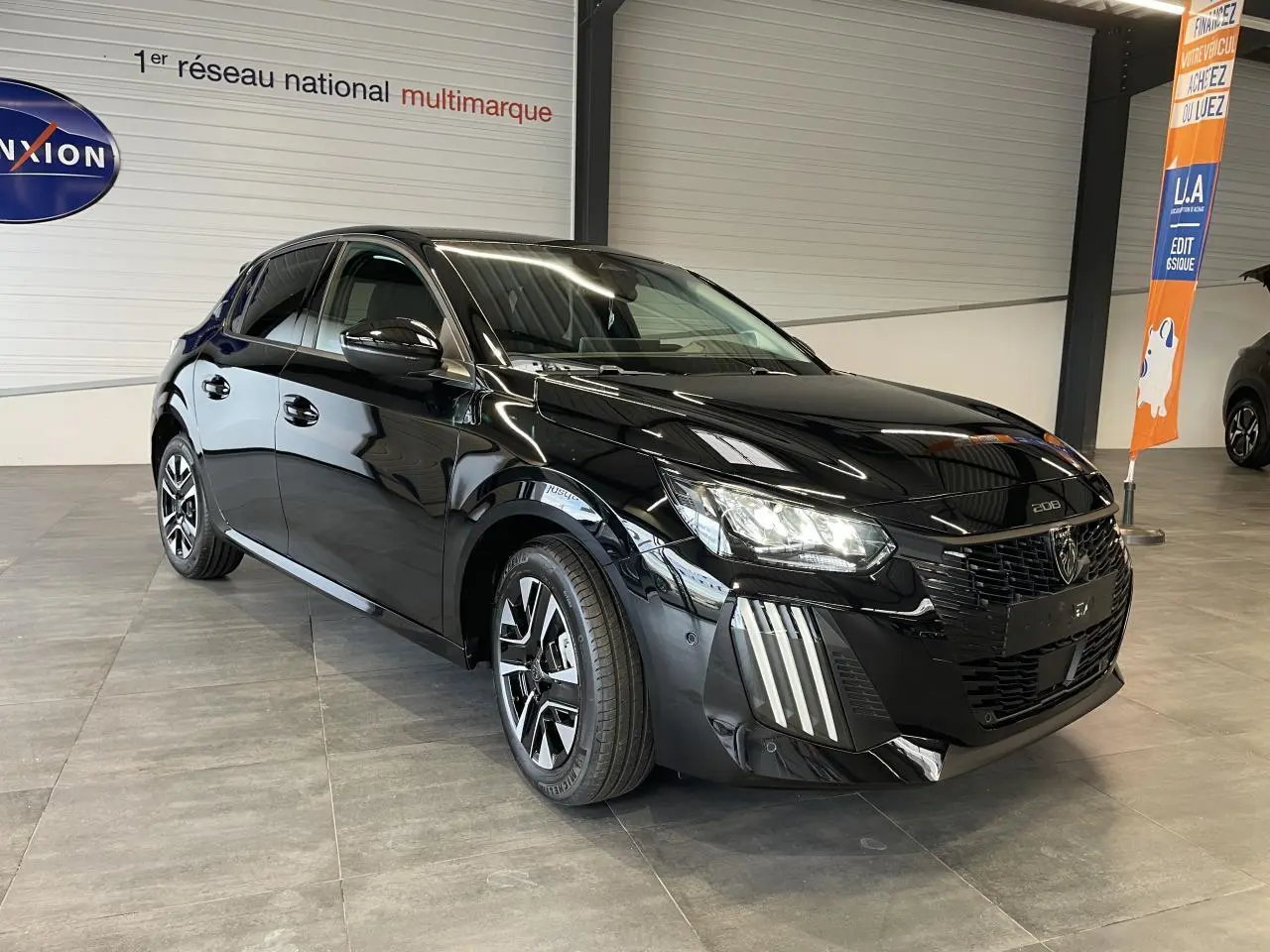 Peugeot 208 noire vue en 3/4 avant droit, avec calandre noire grainée et jantes alliage bi-tons.