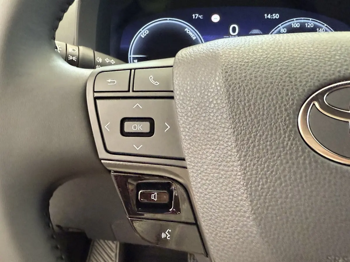 Gros plan sur le volant cuir noir du Toyota C-HR 1.8 Hybride 140 Dynamic avec commandes multifonctions et combiné d'instruments digital.