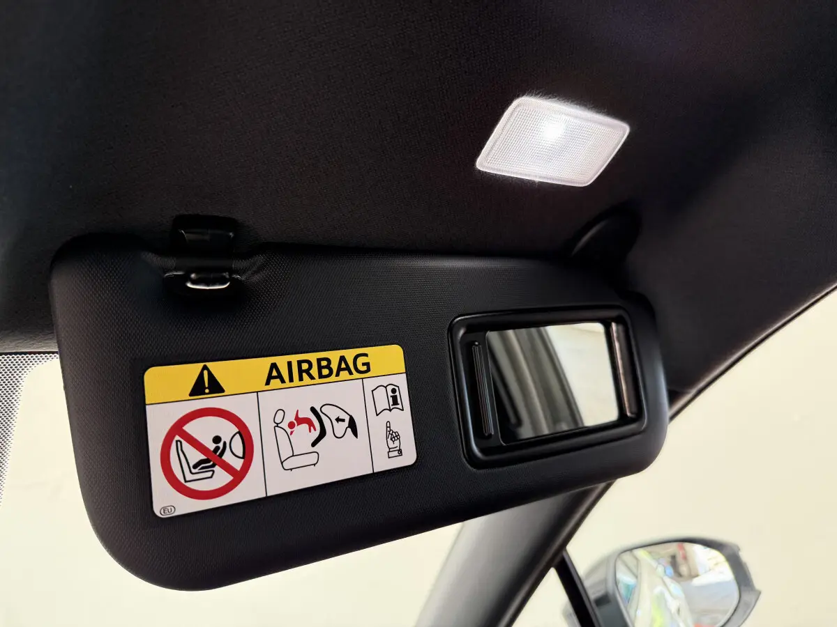 Détail du pare-soleil côté conducteur noir avec miroir et avertissement airbag dans un Toyota C-HR blanc.
