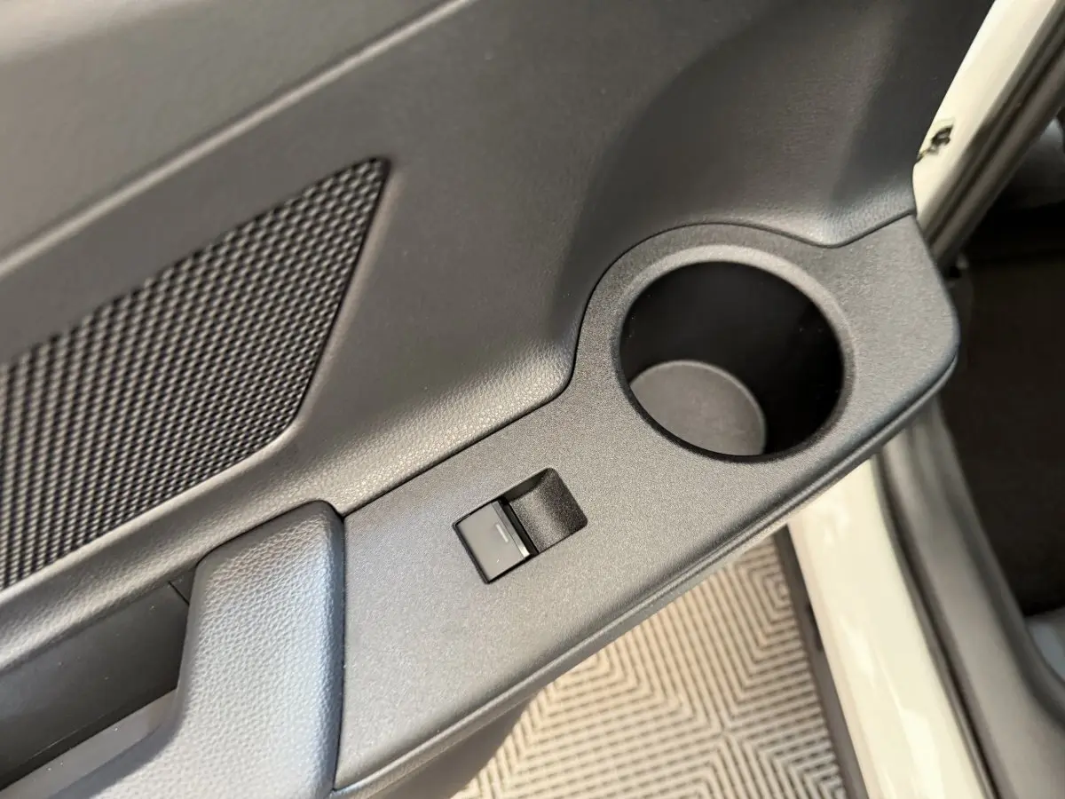 Gros plan sur la porte avant droite blanche du Toyota C-HR 2024, montrant la commande de vitre et un porte-gobelet intégré.