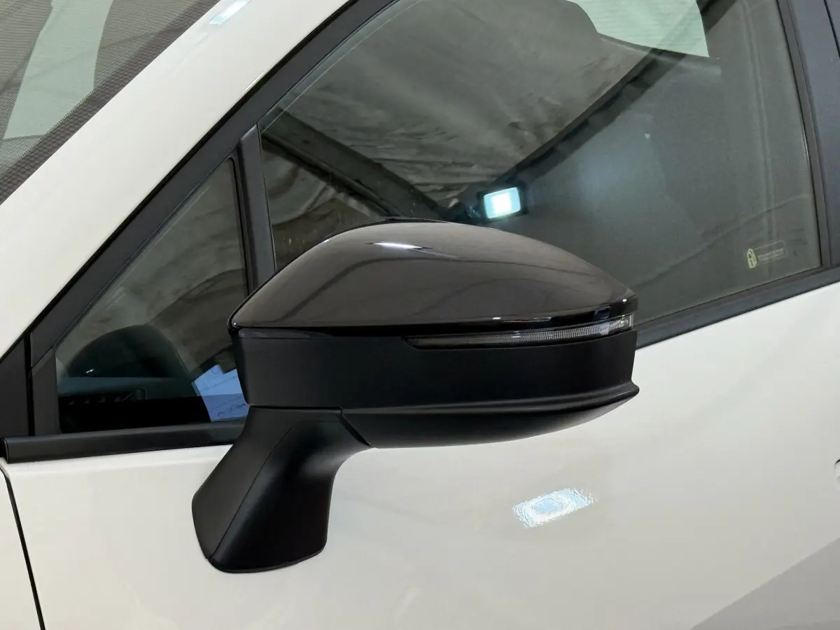 Rétroviseur noir côté gauche du Toyota C-HR blanc 2024, avec clignotant intégré visible sur la coque.