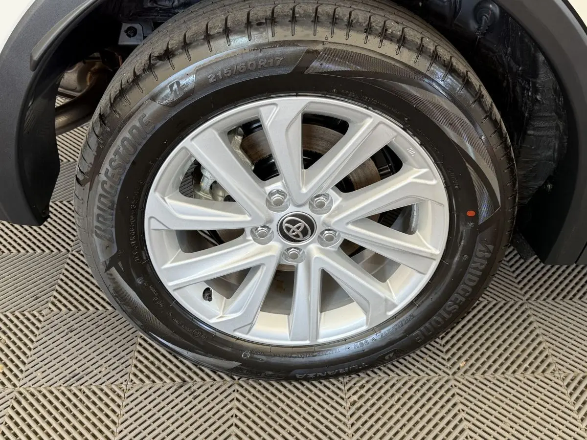 Gros plan sur la roue avant droite du Toyota C-HR 1.8 Hybride blanc avec jante alliage argentée et pneu Bridgestone.