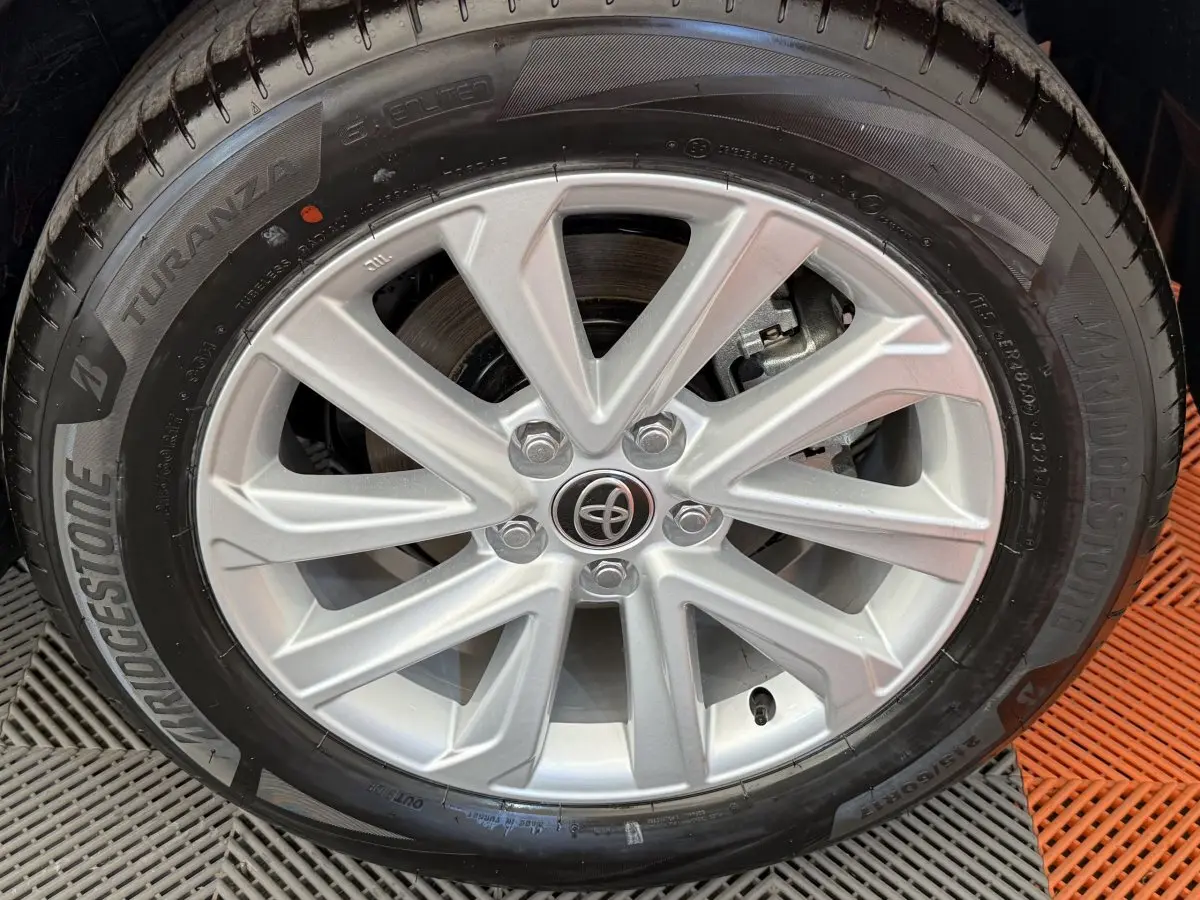 Gros plan sur la jante alliage argentée avec logo Toyota au centre, montée sur un pneu Bridgestone noir.