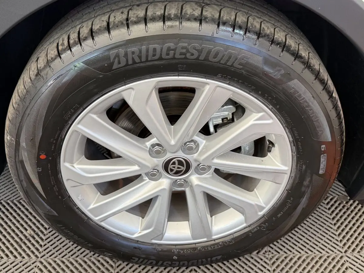 Gros plan sur la roue avant droite du Toyota C-HR blanc 2024 avec jante alliage et pneu Bridgestone Turanza.