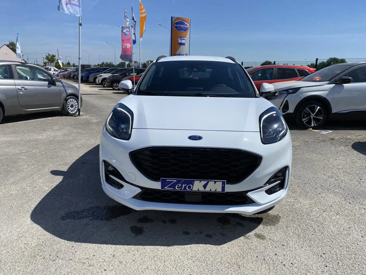 Vue avant d'un Ford Puma blanc glacier avec calandre noire et barres de toit noires sur parking extérieur.