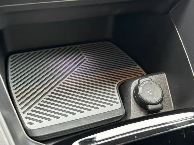 Gros plan sur la prise 12V et un tapis antidérapant noir dans le rangement central du Citroën C4 X Gris Mercury 2025.