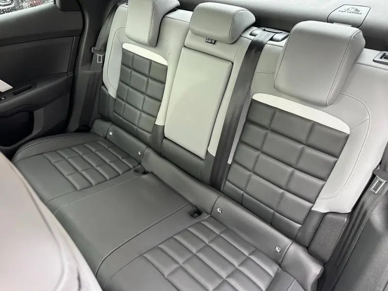 Vue intérieure arrière des sièges en cuir bicolore gris et noir du Citroën C4 X 1.2 Hybride 2025, avec appuie-têtes et ceinture.