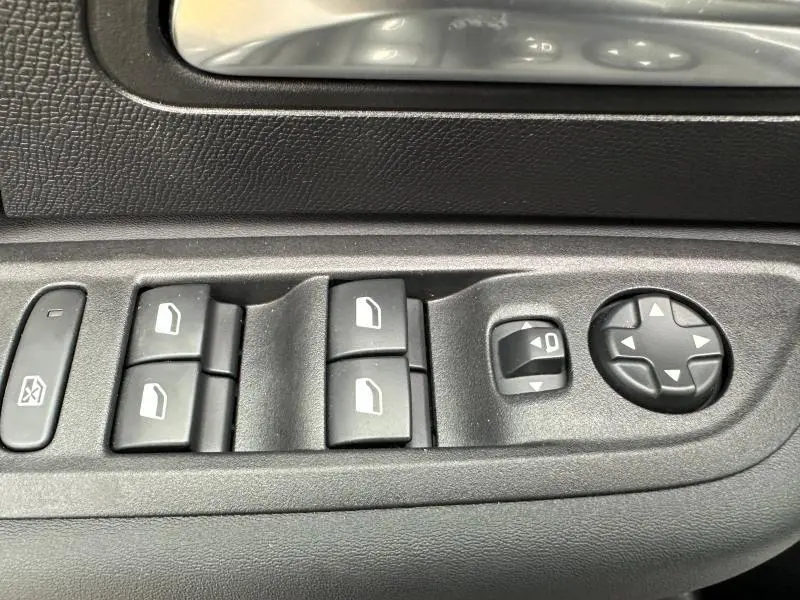 Gros plan sur les commandes des vitres et rétroviseurs du côté conducteur d'une Citroën C4 X gris Mercury 2025.
