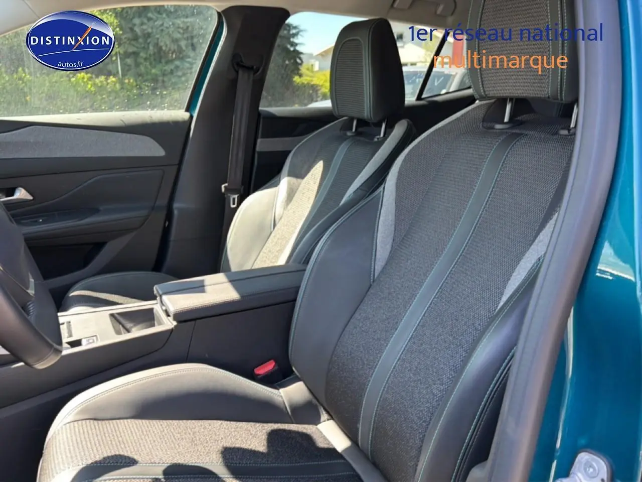 Vue intérieure côté droit des sièges avant en tissu et cuir du Peugeot 408 Hybrid 145 allure bleu 2025 avec accoudoir central.