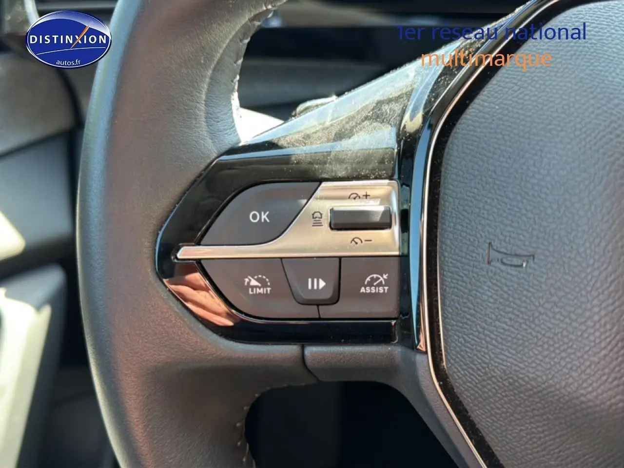 Gros plan sur les commandes multifonctions à gauche du volant cuir noir du Peugeot 408 Hybrid 145 allure bleu 2025.
