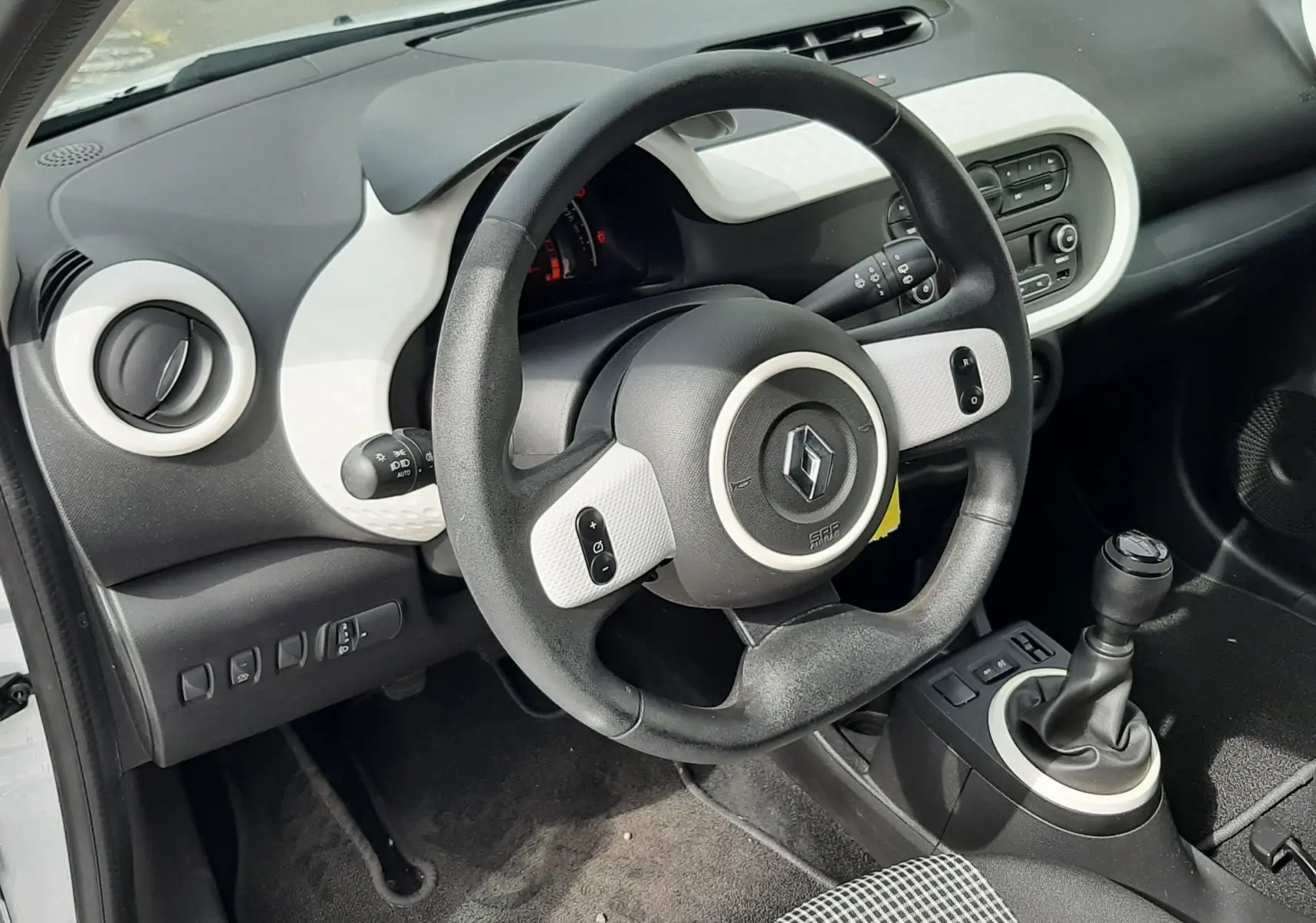 Gros plan sur les commandes de lève-vitres côté conducteur de la Renault Twingo III blanc cristal, finition tissu gris-noir.