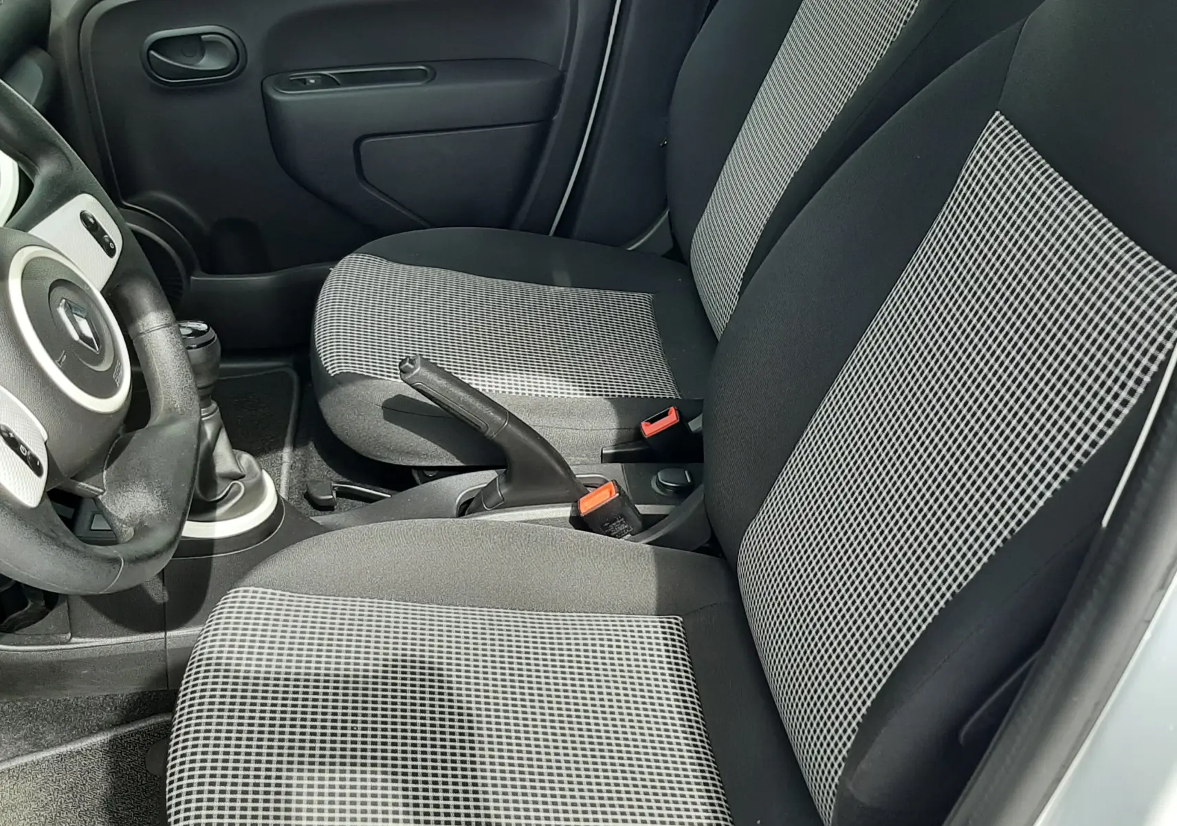 Vue intérieure côté conducteur de la Renault Twingo III blanc cristal, volant multifonction et levier de vitesse manuel visibles.