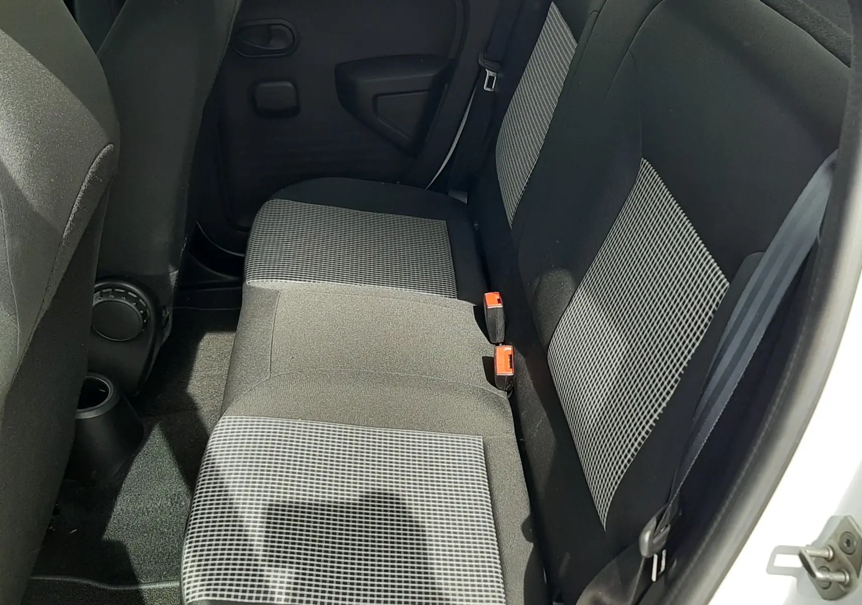 Vue intérieure côté gauche des sièges avant en tissu gris noir de la Renault Twingo III blanc cristal, avec volant et frein à main visibles.