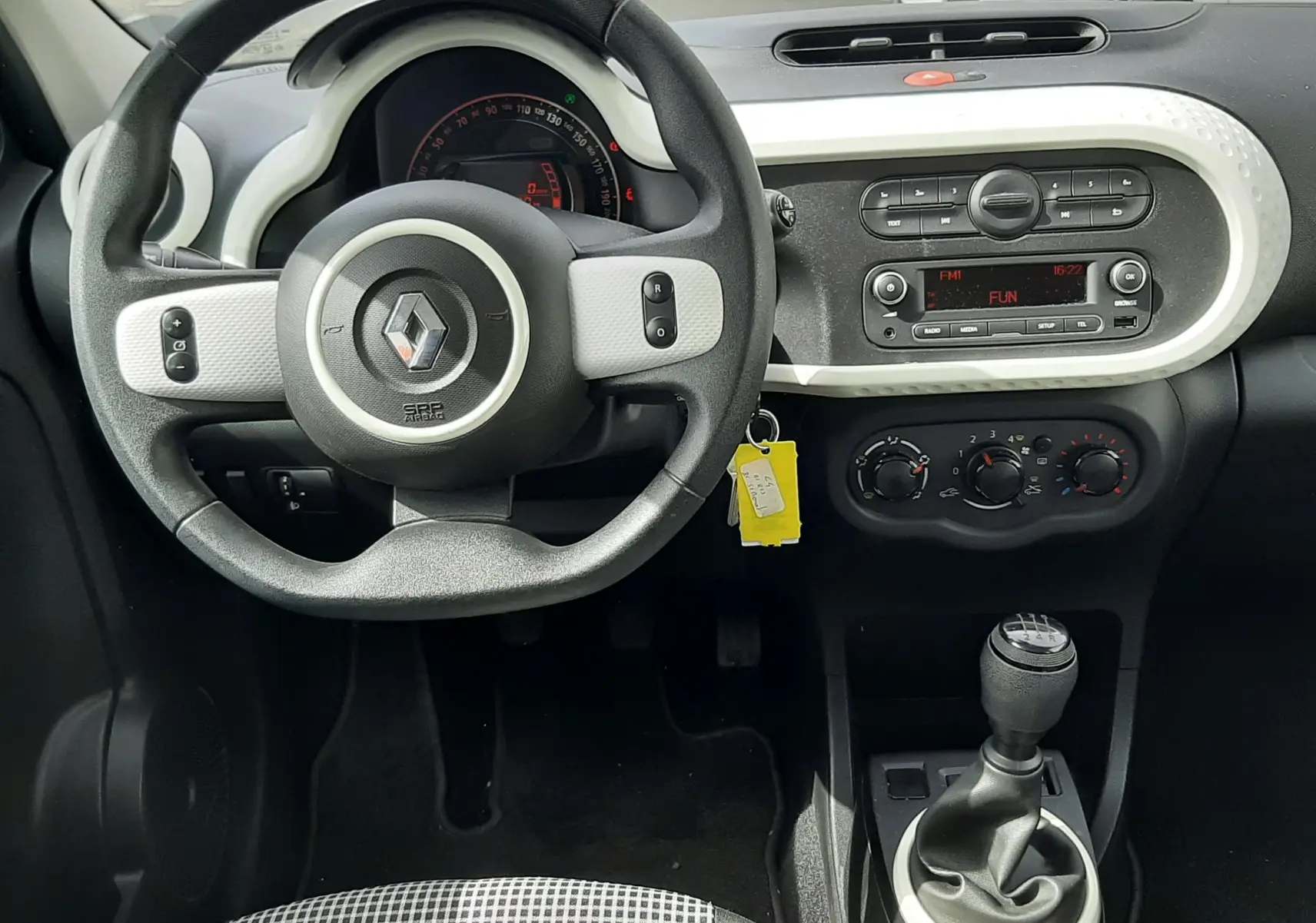 Vue intérieure côté droit des sièges arrière en tissu gris noir de la Renault Twingo III blanc cristal, avec ceintures de sécurité visibles.