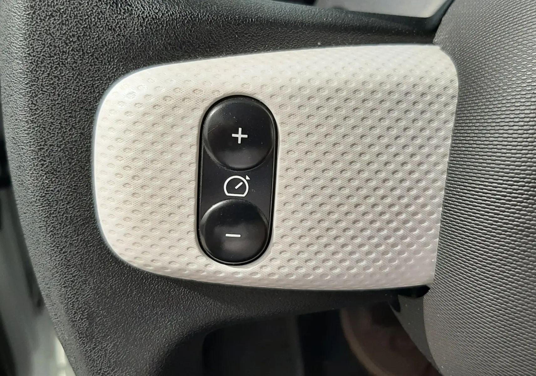 Panneau de commandes intérieures noires avec interrupteurs et molette de réglage des phares dans une Renault Twingo III blanc cristal.