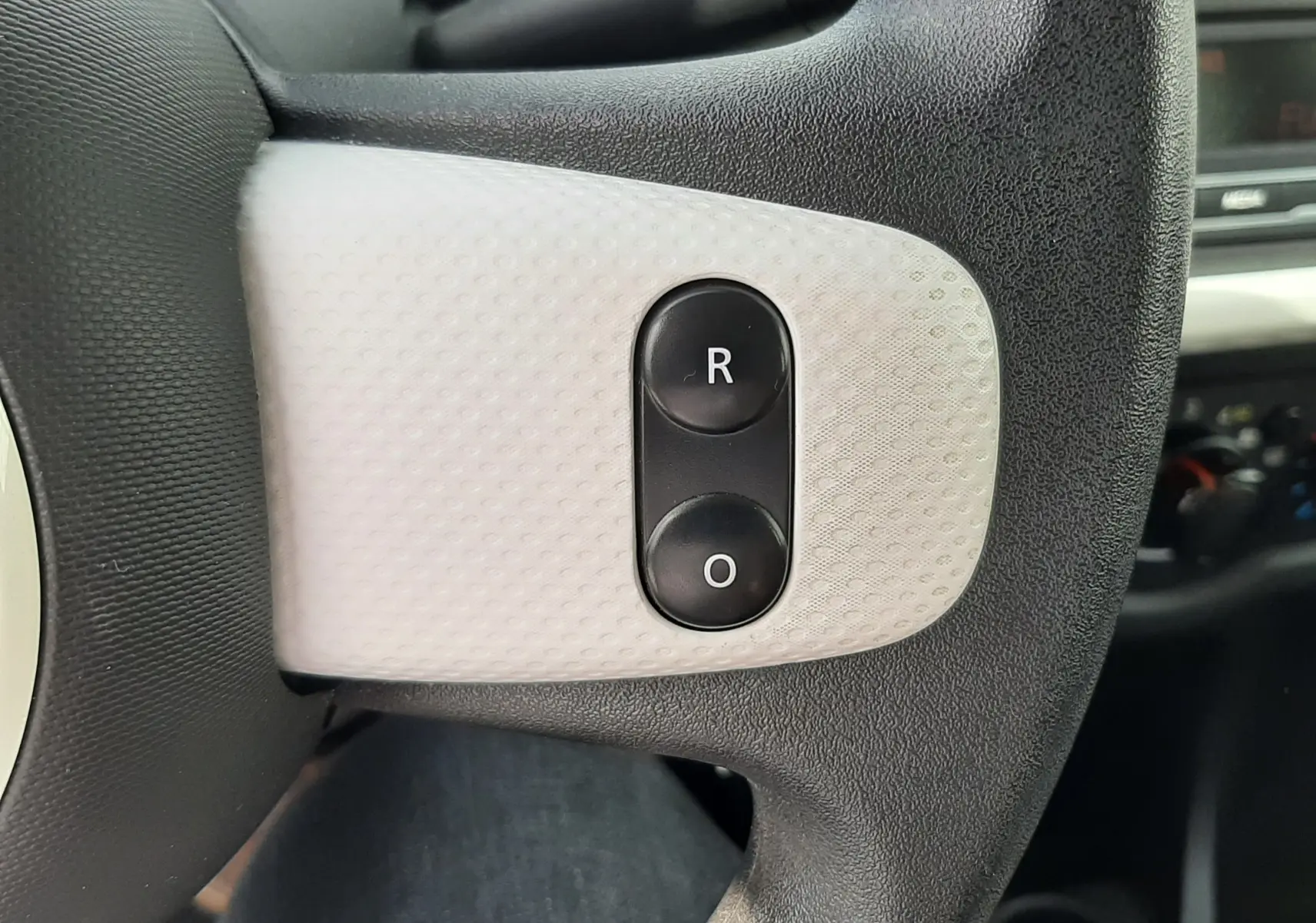 Gros plan sur les boutons de réglage des rétroviseurs sur le volant d’une Renault Twingo III blanc cristal.