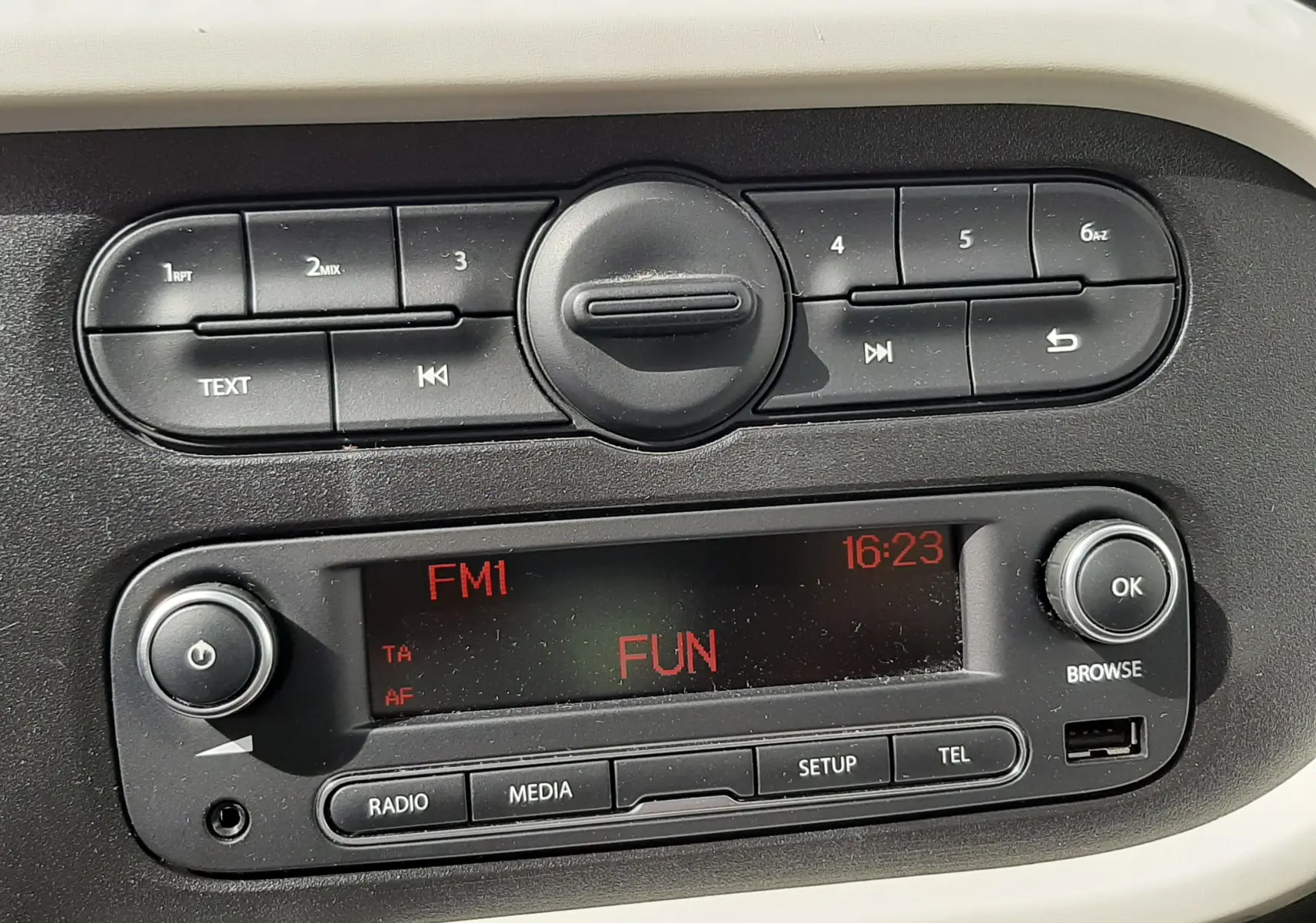 Vue rapprochée des commandes de climatisation noires sur tableau de bord gris d'une Renault Twingo III blanche.