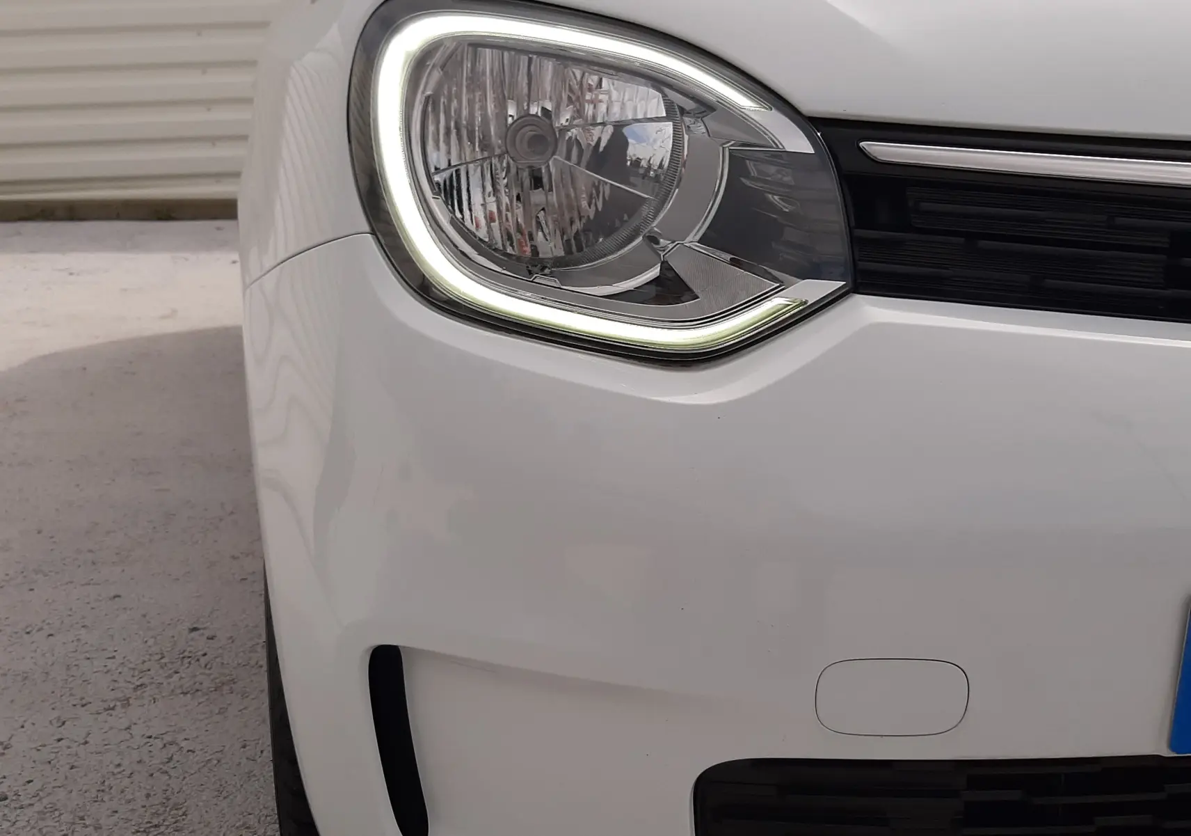 Vue de côté droit avant d'une Renault Twingo III blanc cristal, mettant en valeur les poignées noires et les vitres teintées.